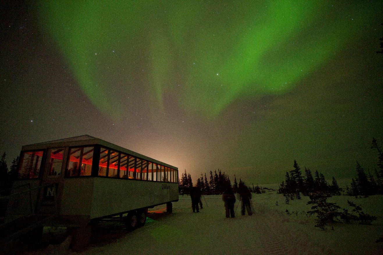 a wispy display of northern lights over the aurora pod