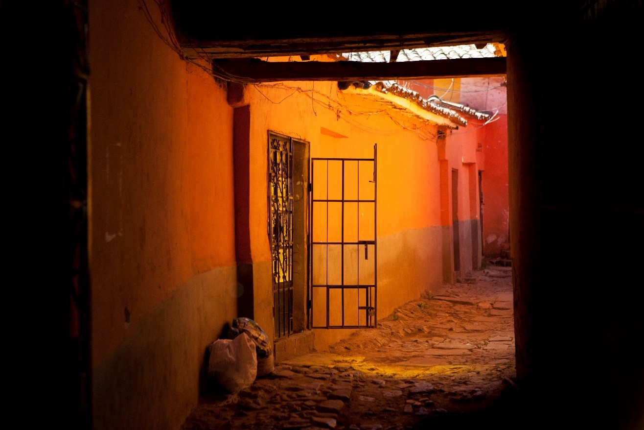 an alley in cusco is illuminated in fascinating orange and red with shadows framing the foreground
