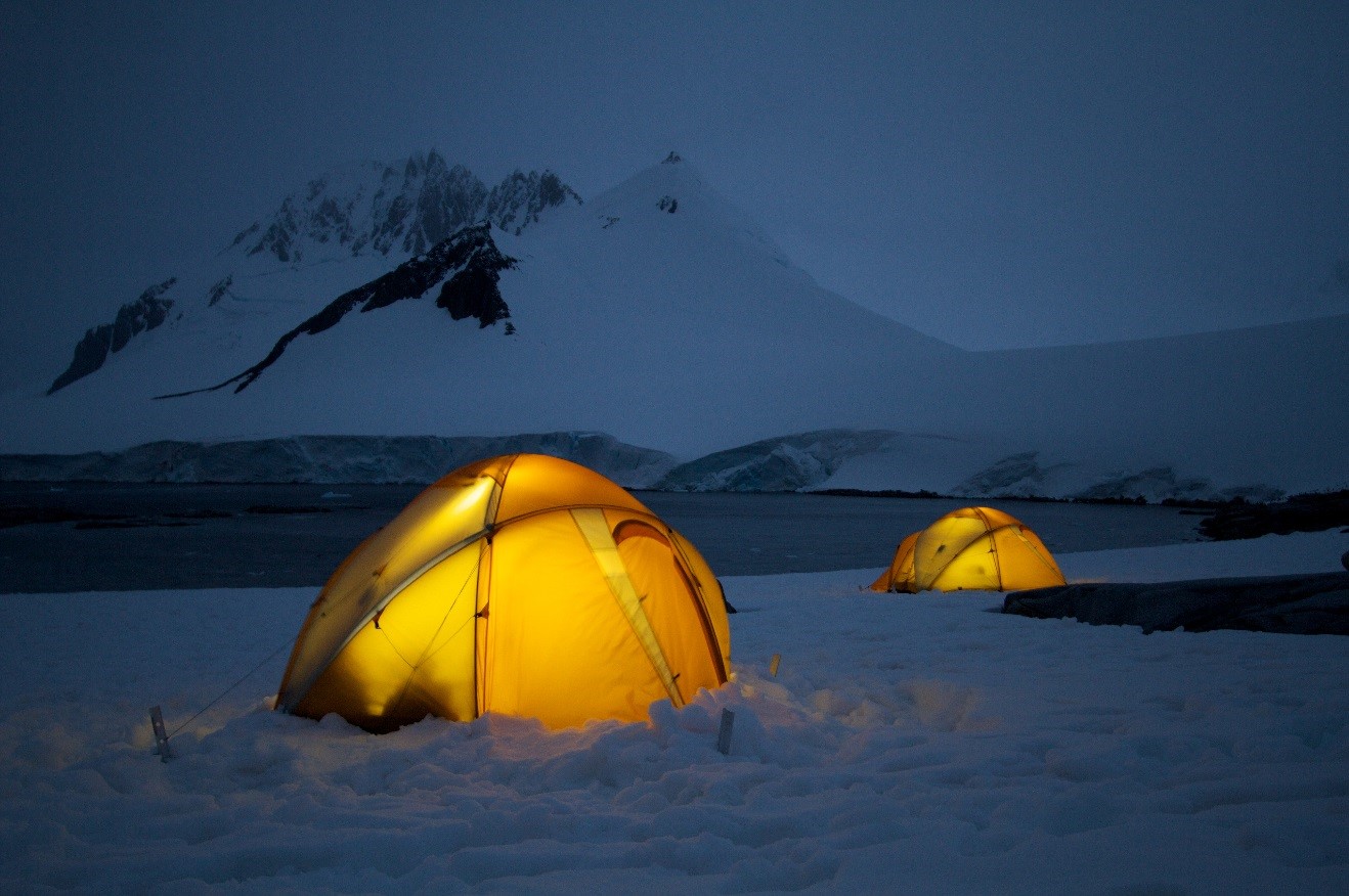 two glowing yellow tents photographed at the blue hour on the mainland of antarctica