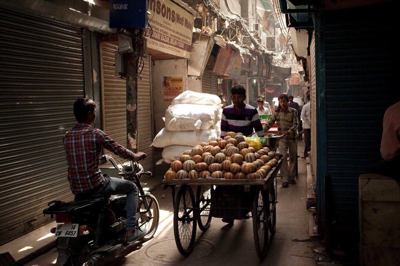 a dimly lit photo of the streets of new delhi with a vendor pushing a cart