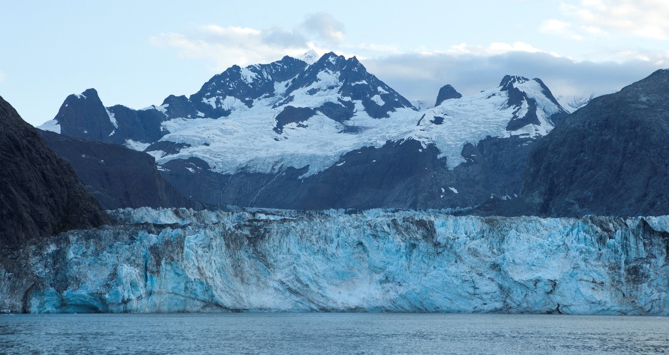 a stunning glacier with a towering mountain in the background in Glacier Bay, Alaska