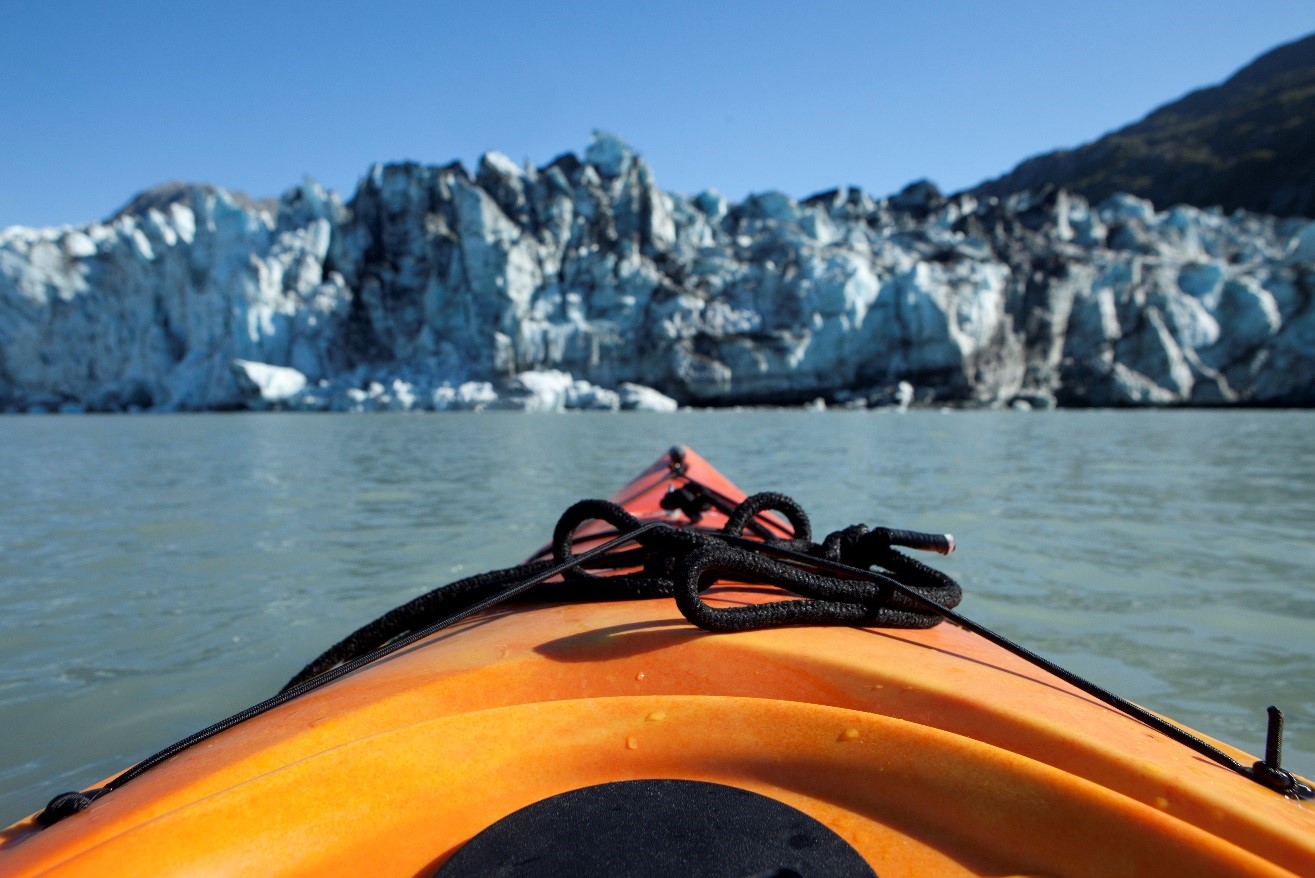 a kayak is pointed towards a glacier in an adventurous photo