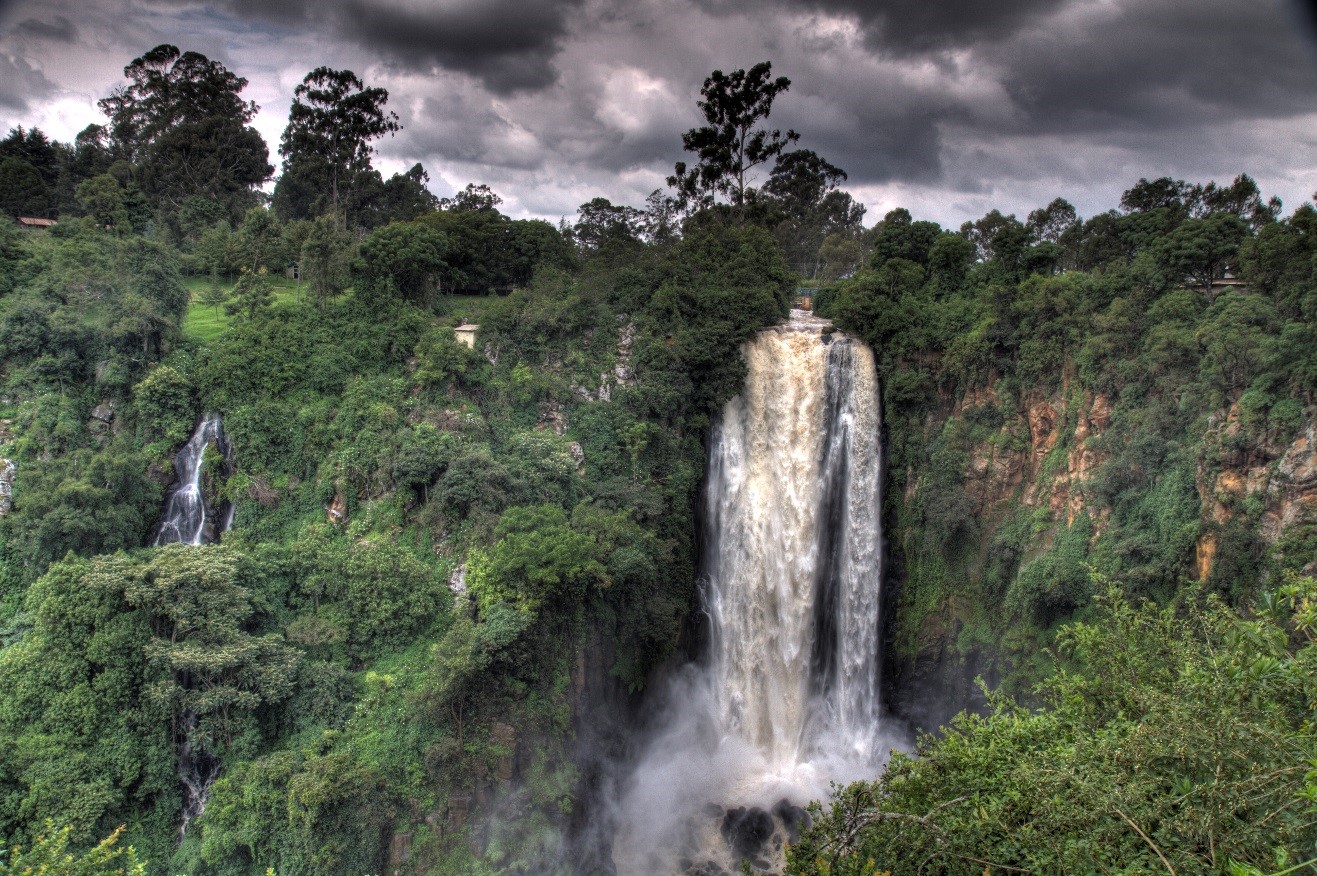 an ominous photo of a waterfall in kenya with storm clouds overhead