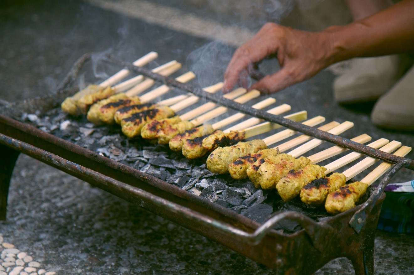 a shallow depth of field photo of chicken satay grills on a small grill