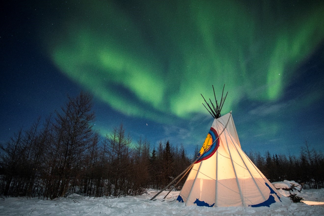 a lone tipee sits on the snow with northern lights overhead in the arctic