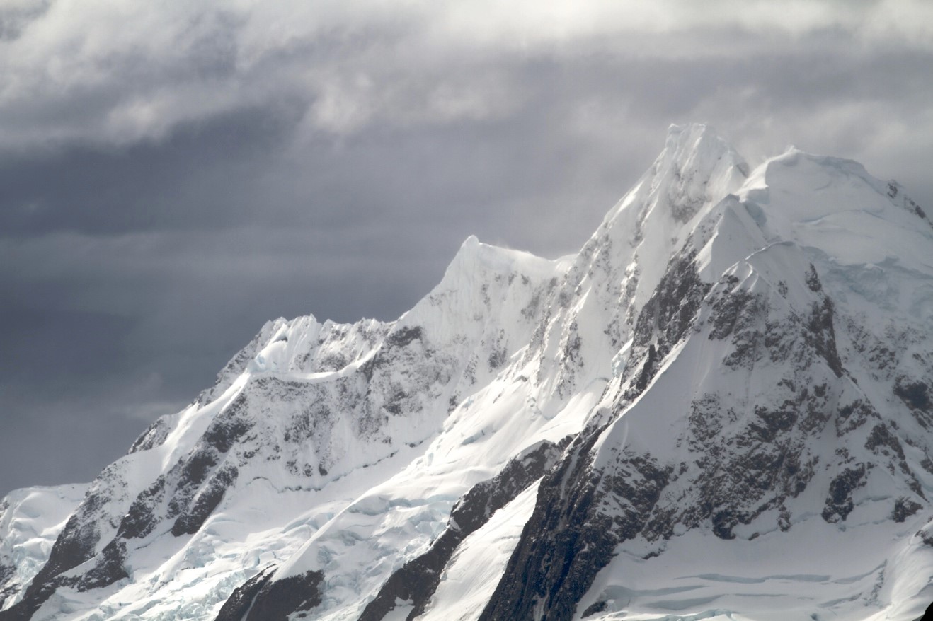 dramatic photo of jagged mountain peaks and clouds in antarctica