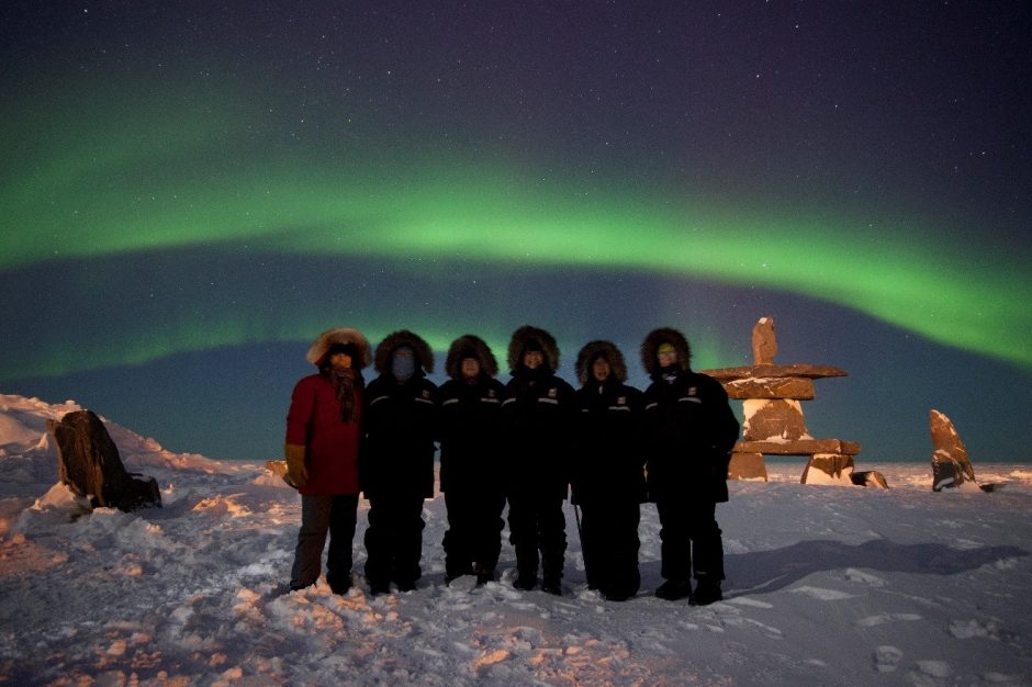 a group of travelers in front of the northern lights in Churchill Manitoba Canada