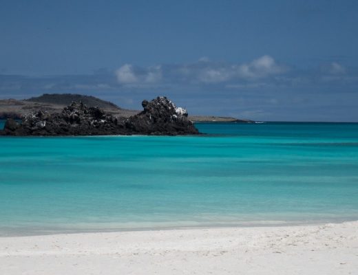 a photo of green water and blue skies over a beach in the galapagos
