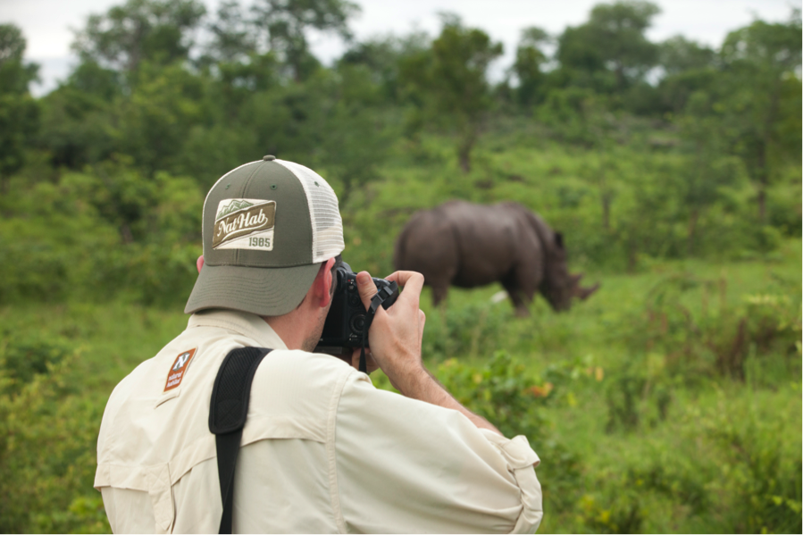 a photographer captures a photo of a rhino at close range while on foot in mosi oa tunya national park in Zambia