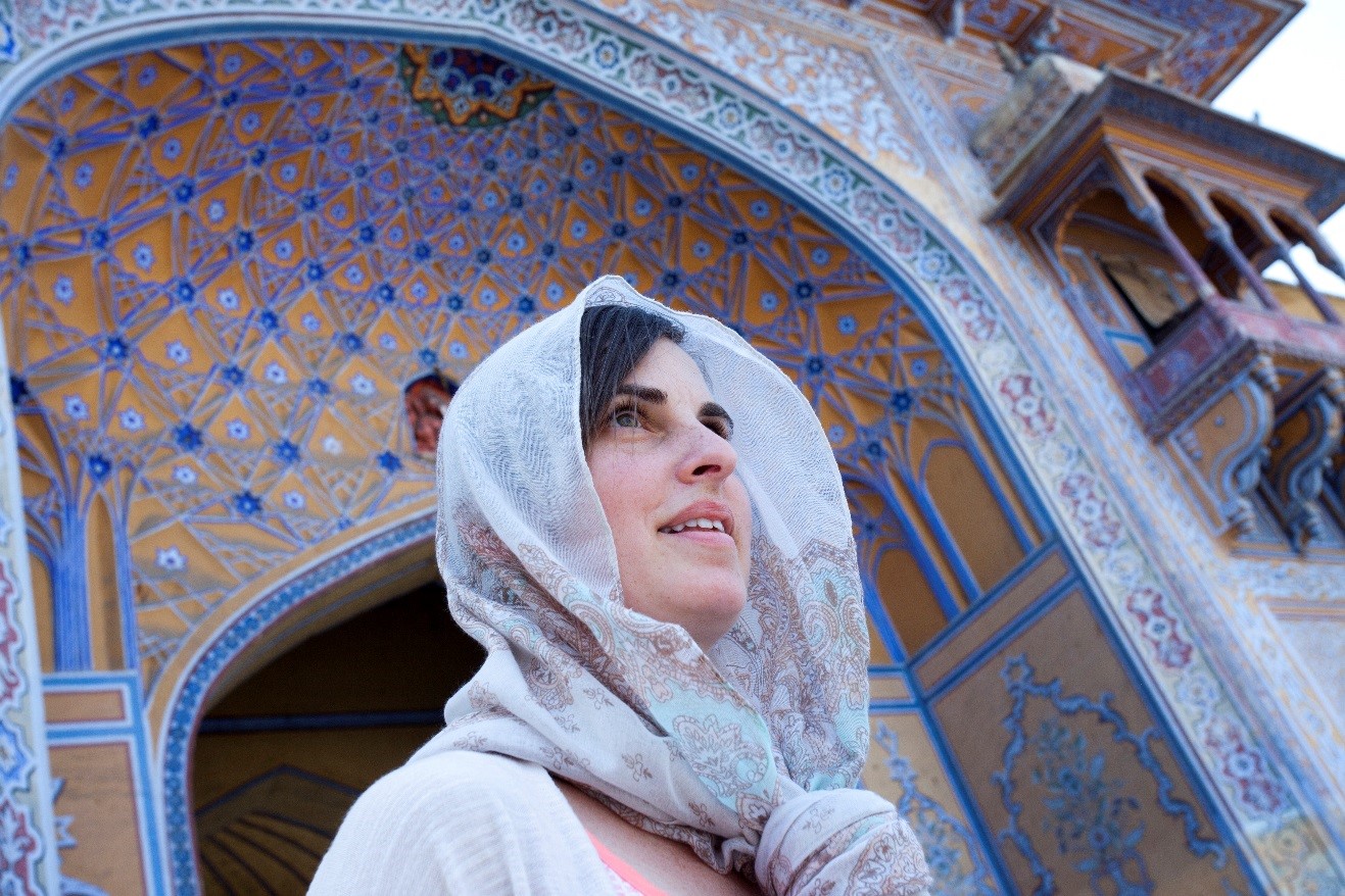 a woman looks intriguingly into the distance while outside of a palace in jaipur, india