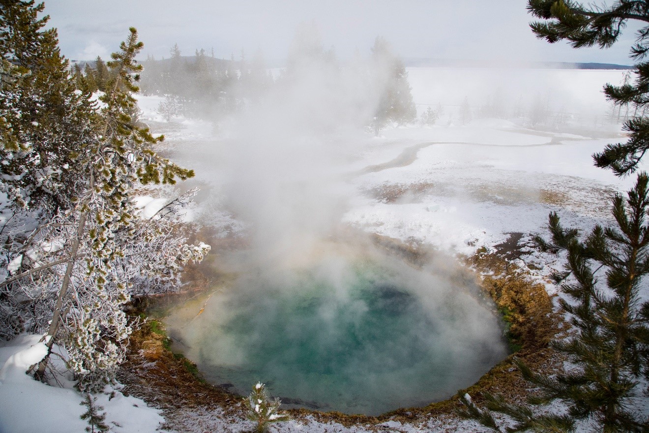 a thermal pool steams during winter in yellowstone