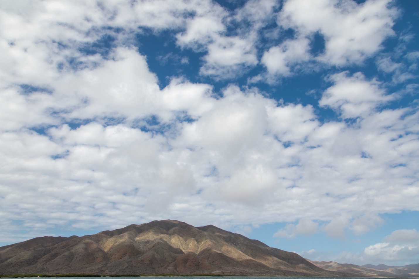 patchy and dramatic clouds above a hill in Baja