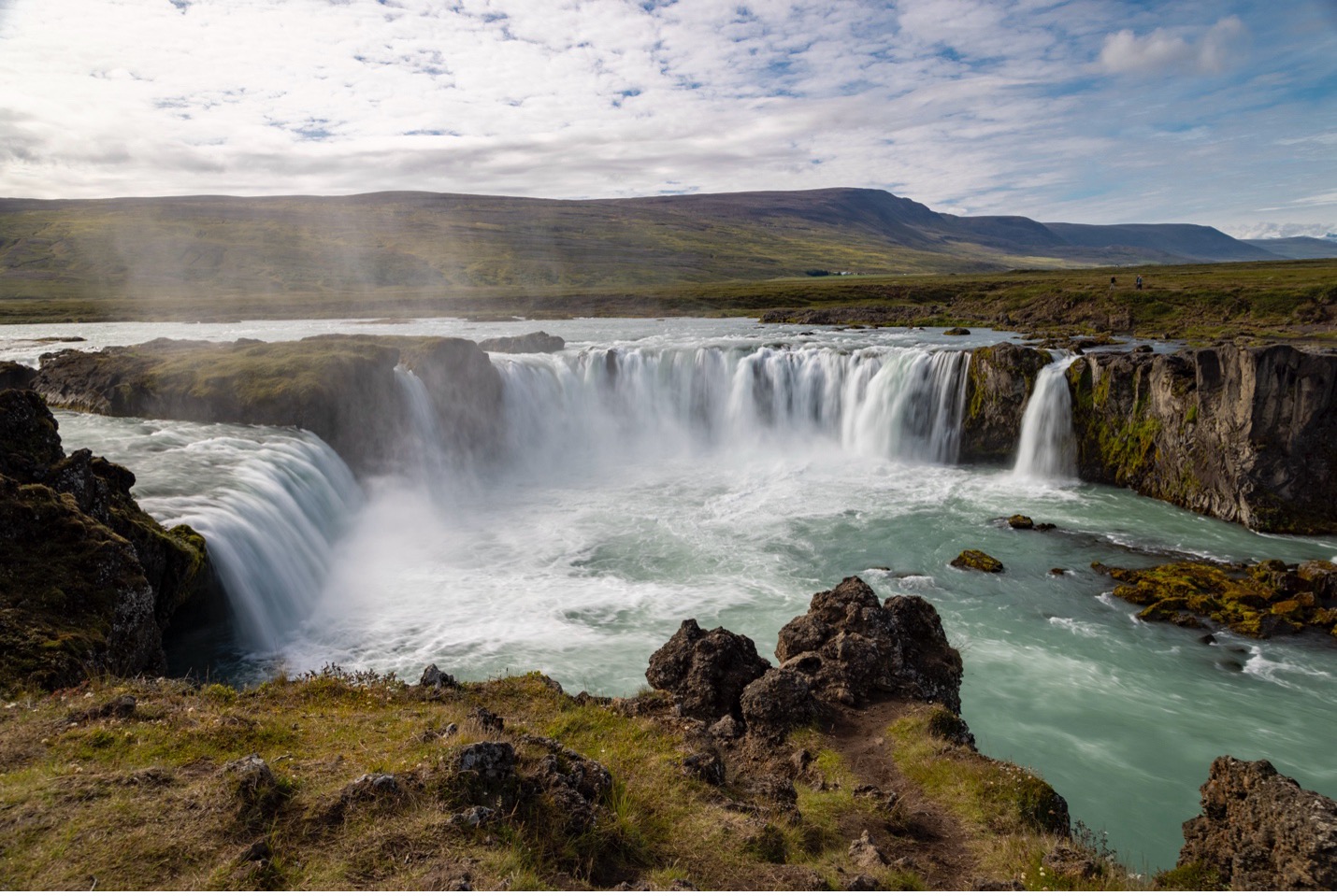 a gorgeous waterfall pours into a river in iceland
