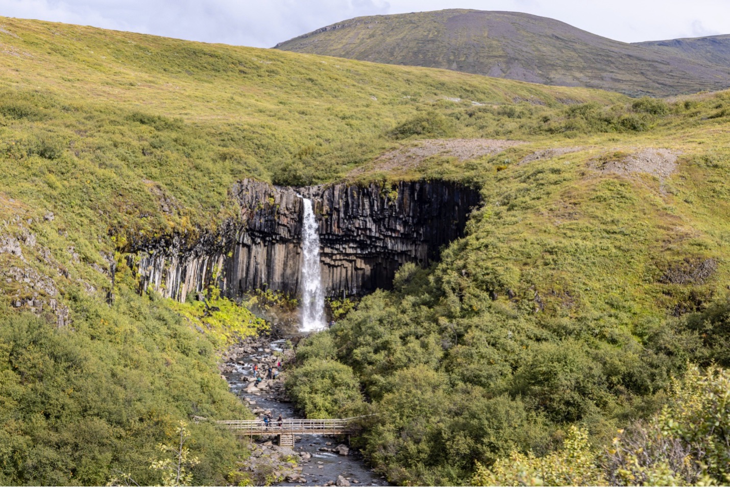 a tall waterfall makes the surrounding scenery look massive