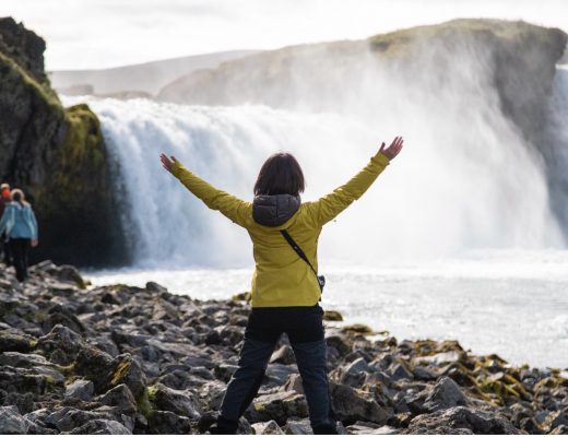 a traveler rejoices in front of a waterfall in iceland