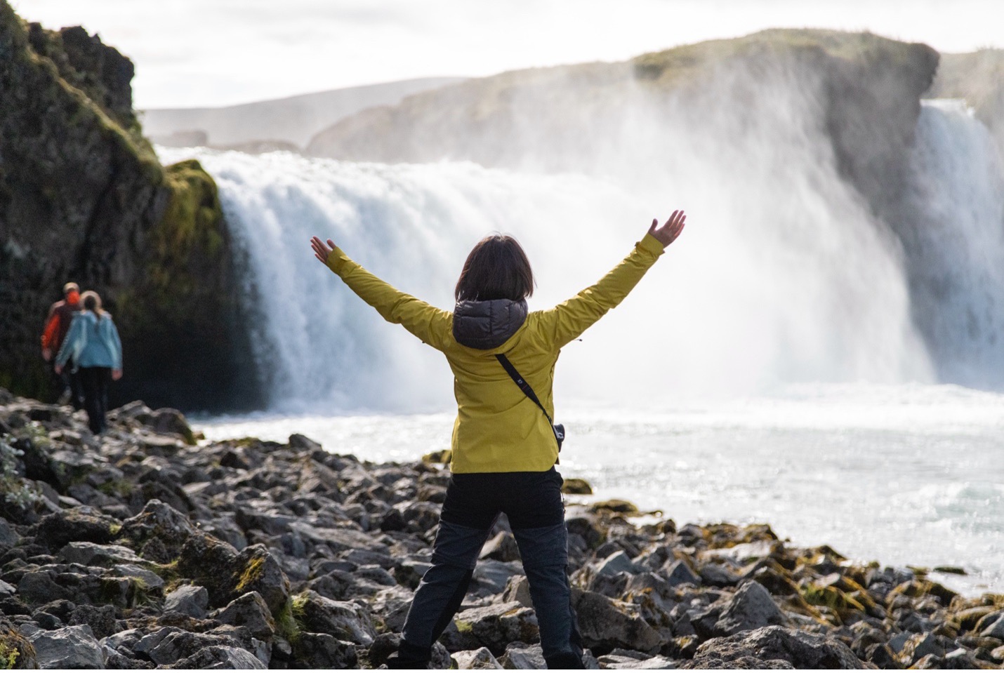 a traveler rejoices in front of a waterfall in iceland