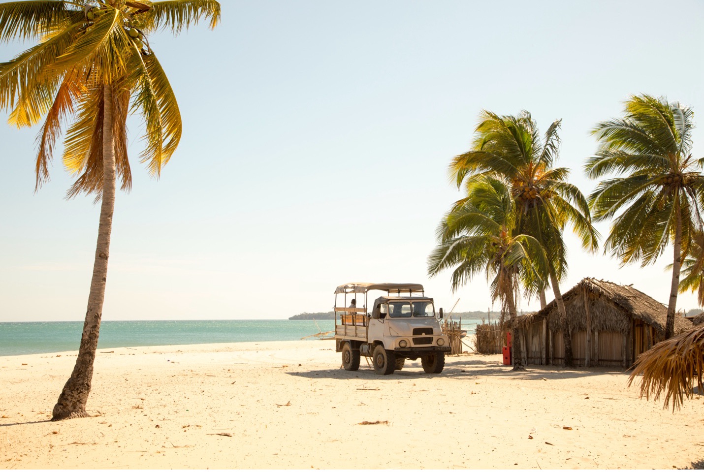 a beach scene with a lone truck beneath palm trees in Madagascar