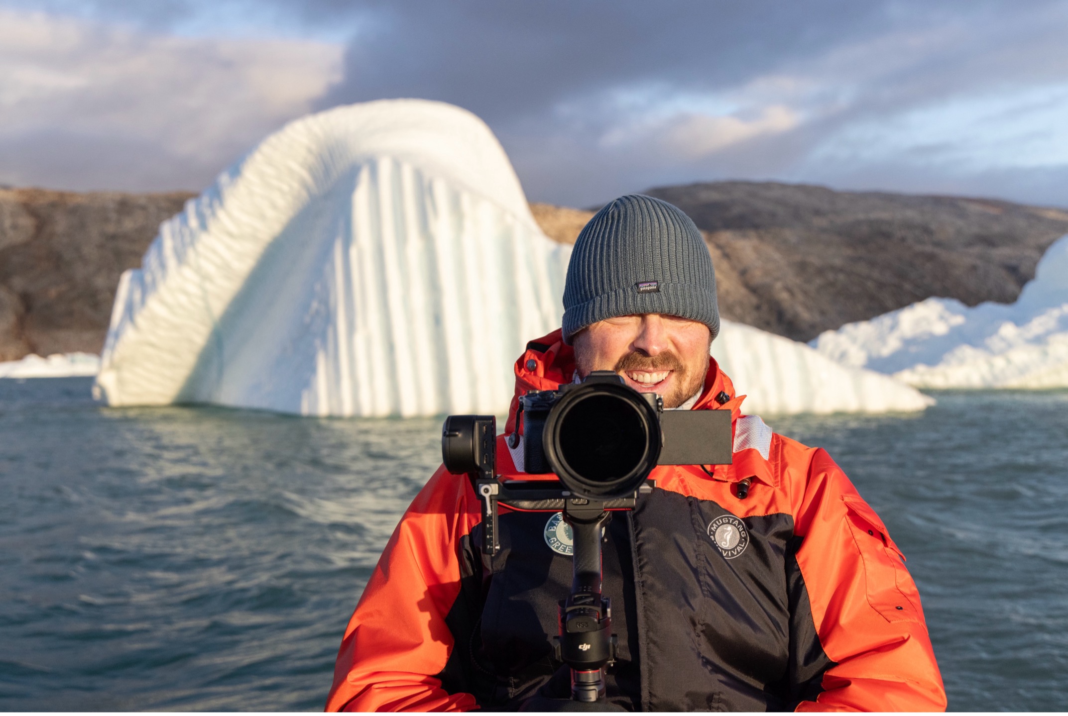 a videographer poses in front of an iceberg in Greenland